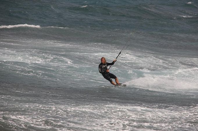  穿着潜水服的男子站在冲浪板上并连接着电缆